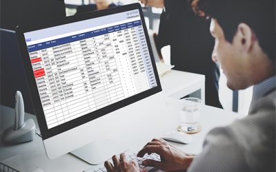 Business person (young woman) works at table with computer - office interior